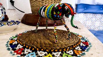 A beaded elephant sculpture on a woven mat, with a basket and a patterned bowl in the background.