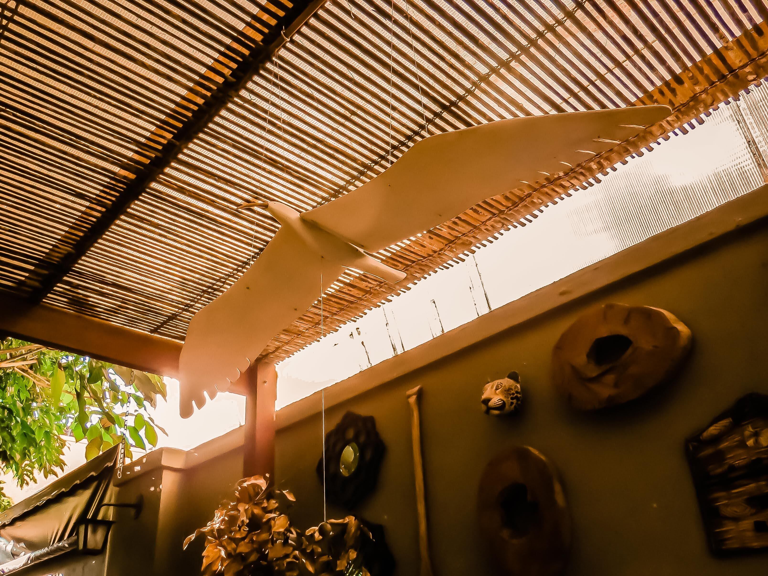 A room with a bamboo ceiling, a ladder, and several decorative masks on the wall.