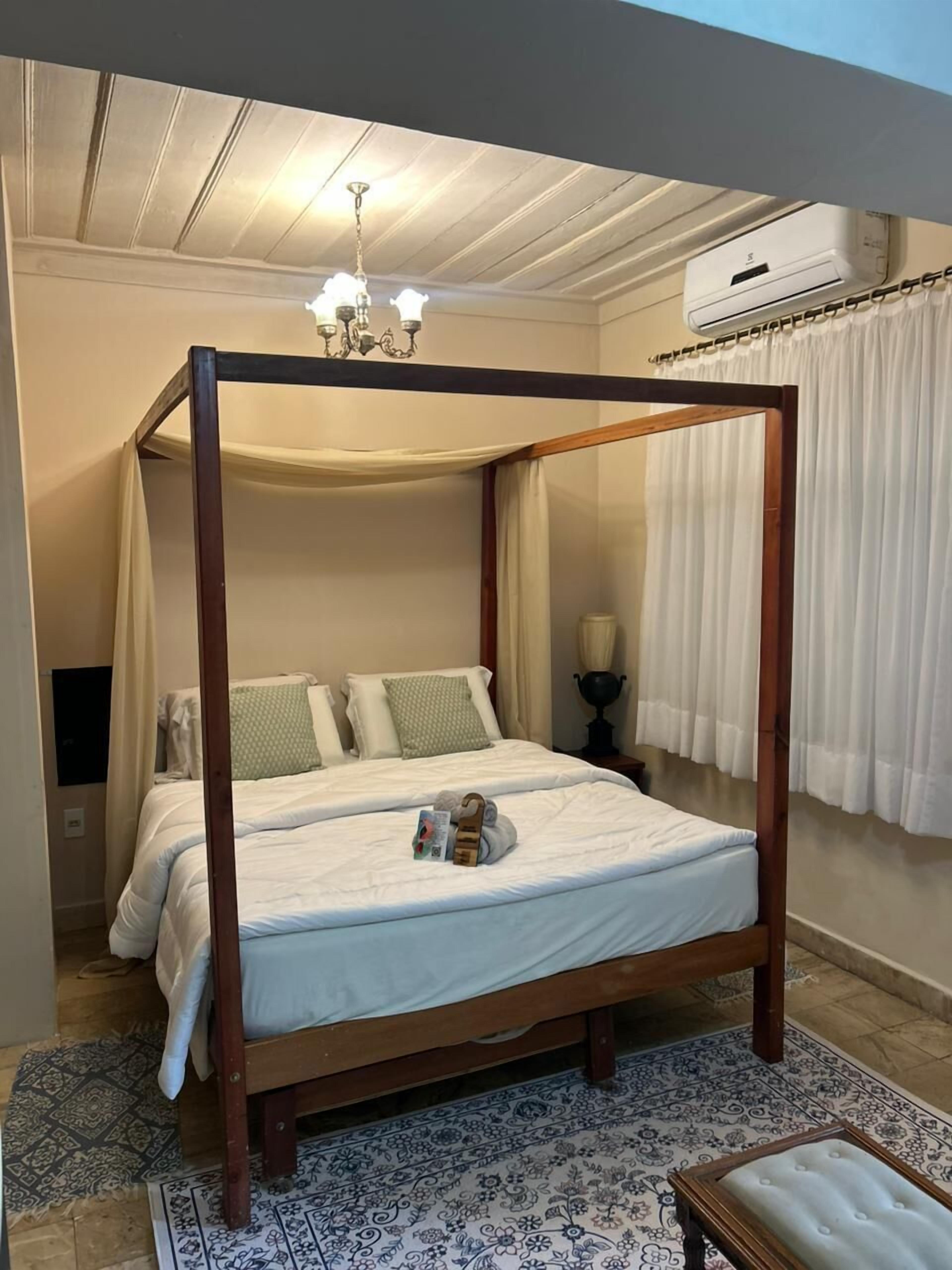 A four-poster bed with a canopy, a chandelier, and a ceiling fan.