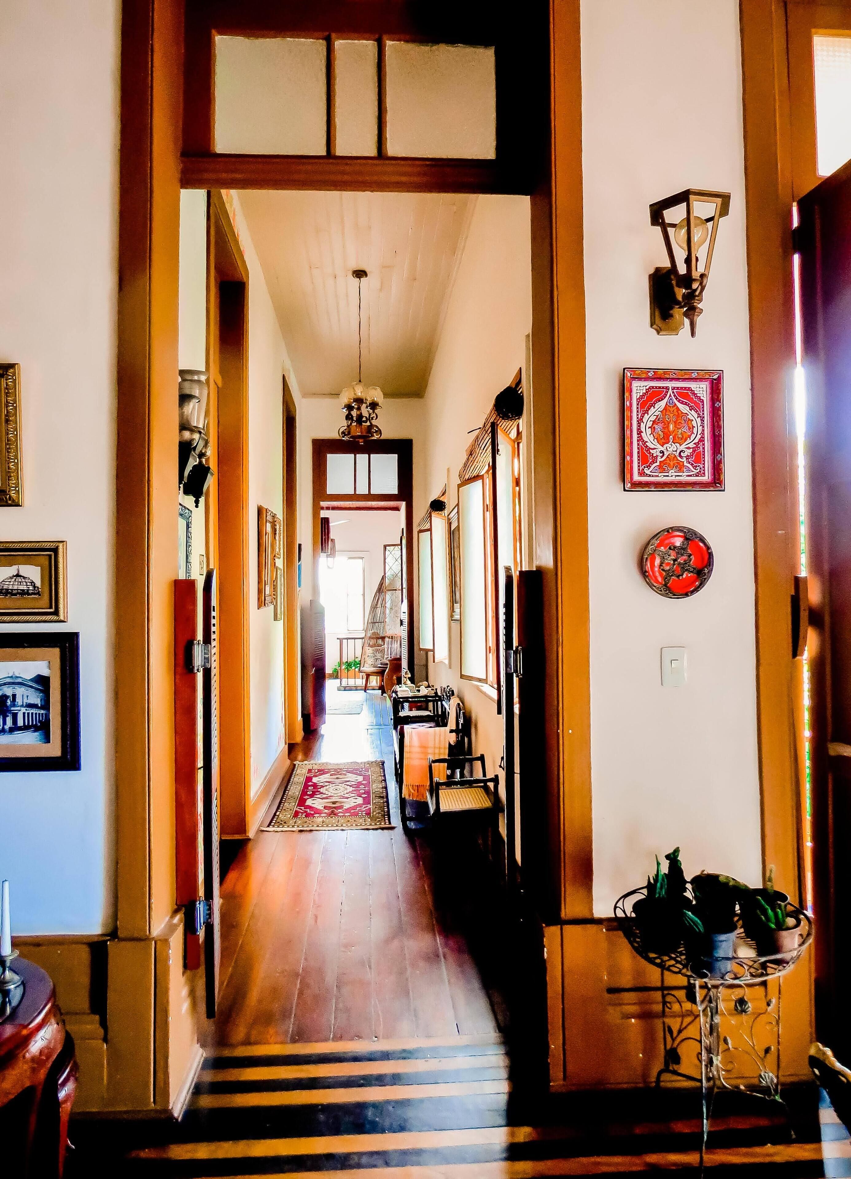 A hallway with wooden flooring, a patterned rug, and a staircase leading to another room.
