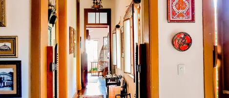 A hallway with wooden flooring, a patterned rug, and a staircase leading to another room.