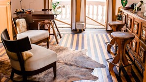 A room with a wooden desk, a chair, a bar area with stools, and a large glass door leading outside.