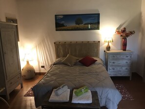 Ein Schlafzimmer mit einem Bett, einem Nachttisch, einer Lampe, einer Kommode und einem Bild an der Wand.