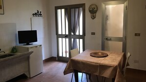 Uma cozinha compacta com pia, uma pequena geladeira, uma televisão e uma área de jantar com mesa e cadeiras.