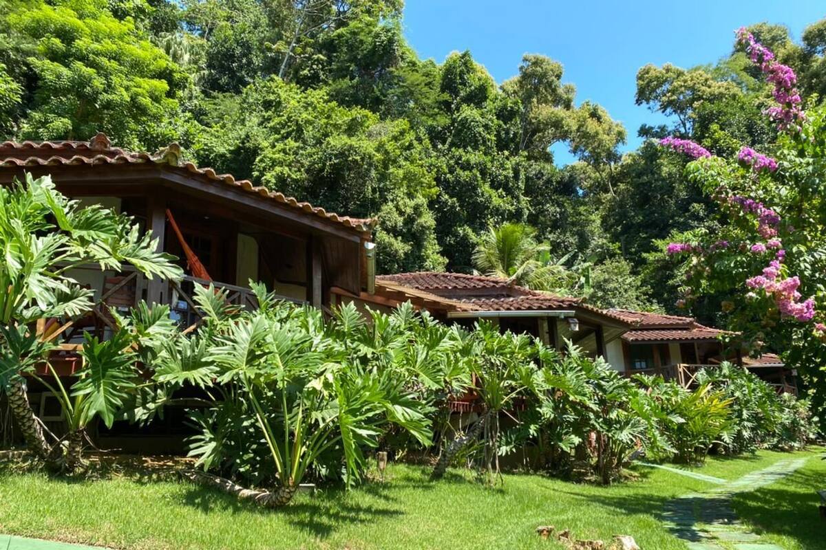 A rustic building with a tiled roof, surrounded by lush greenery and tropical plants.