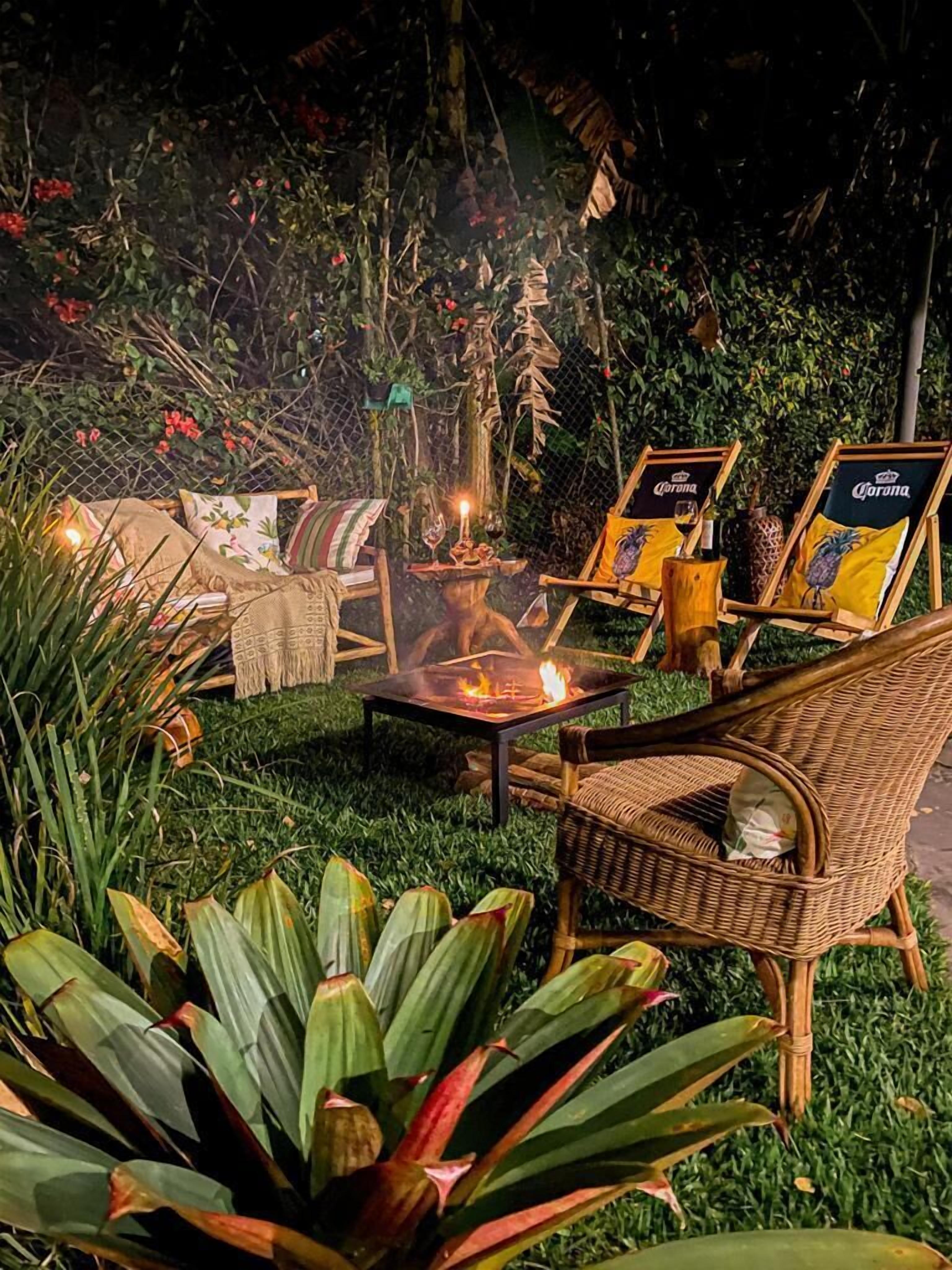 Een terras met rieten stoelen, een vuurkorf en een tafel met een kaars.