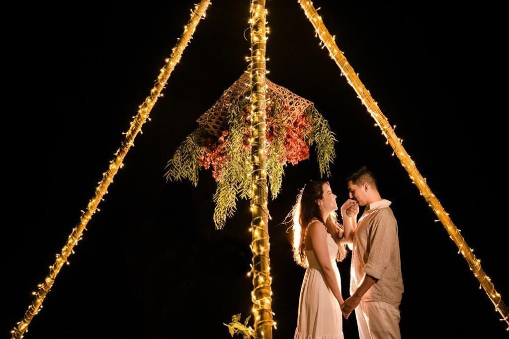 A couple under a decorative canopy with lights, suggesting a romantic setting.