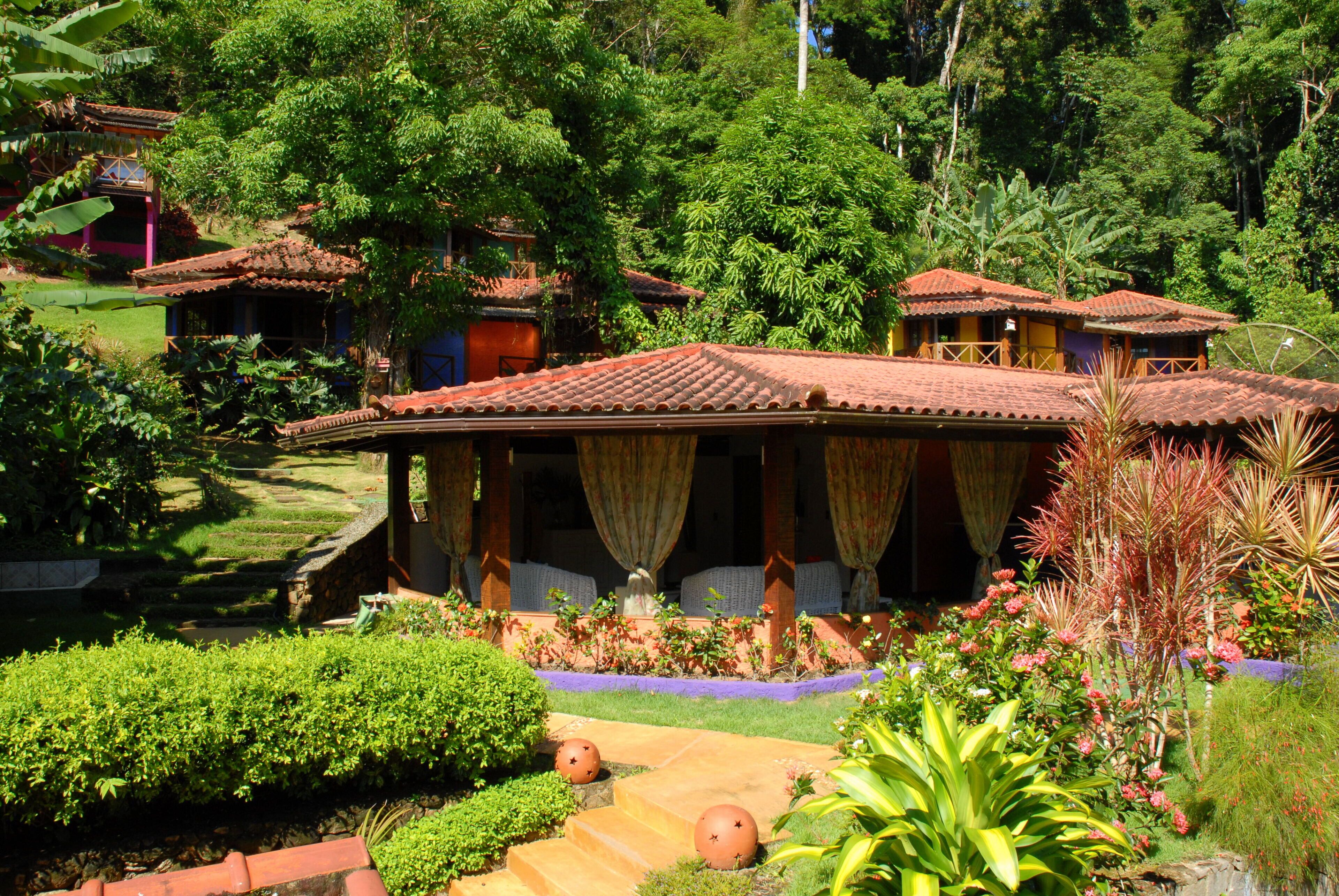 Un edificio de estilo tradicional con tejado de tejas, rodeado de abundante vegetación y un jardín bien cuidado.