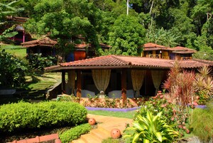Un edificio de estilo tradicional con tejado de tejas, rodeado de abundante vegetación y un jardín bien cuidado.