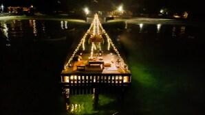 Un barco con cubierta y barandilla, flotando sobre el agua, con luces que se reflejan en la superficie.