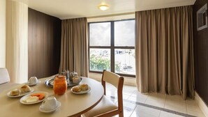 Un coin repas avec une table ronde, des chaises et une fenêtre avec des rideaux.