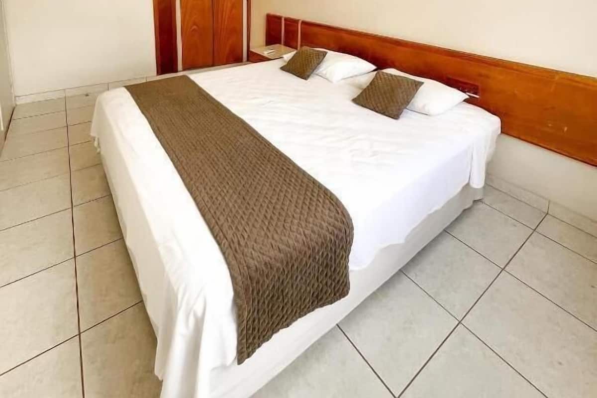 A hotel room with a large bed, wooden headboard, and a wardrobe.