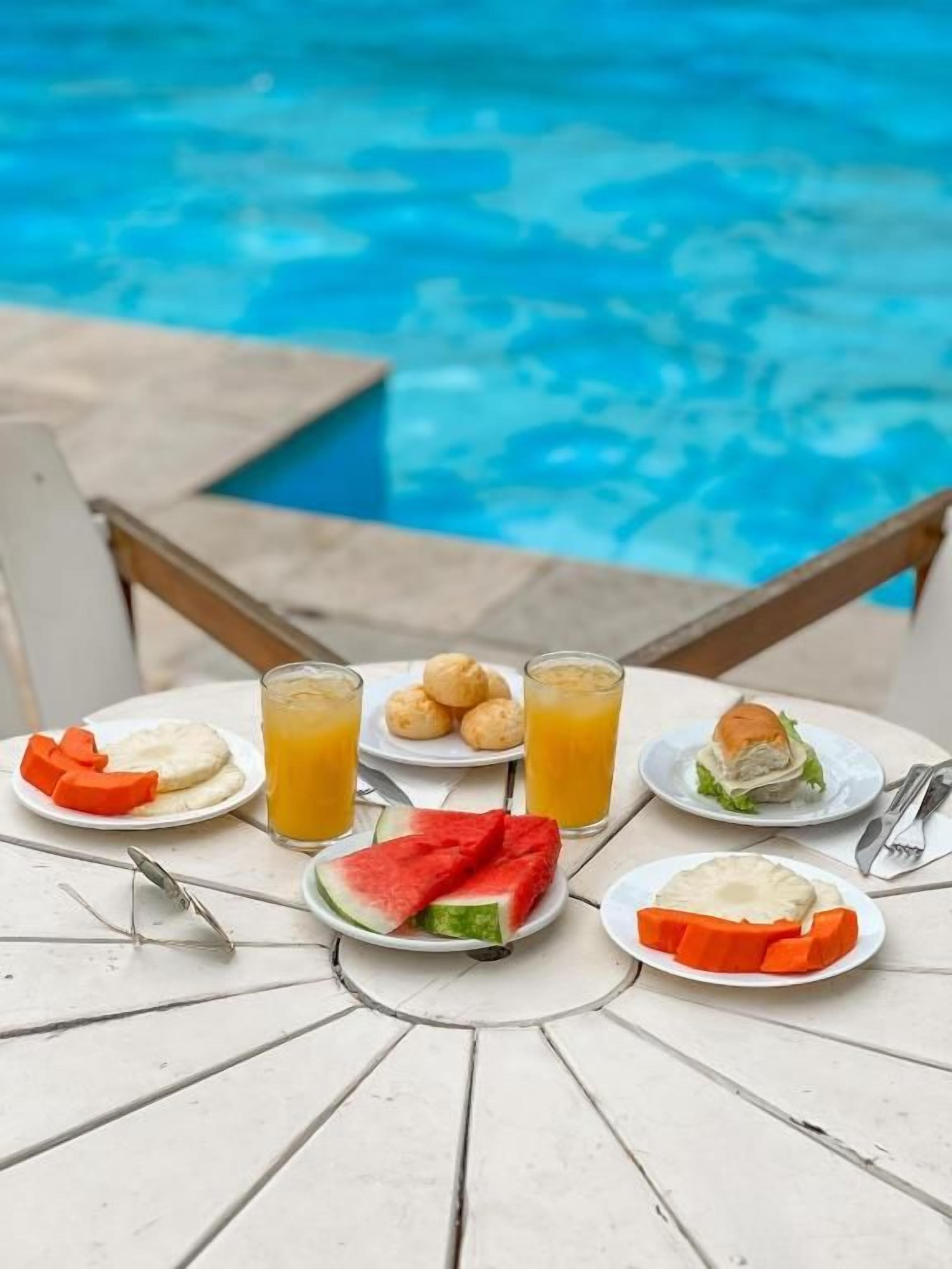 A table with food and drinks near a pool.