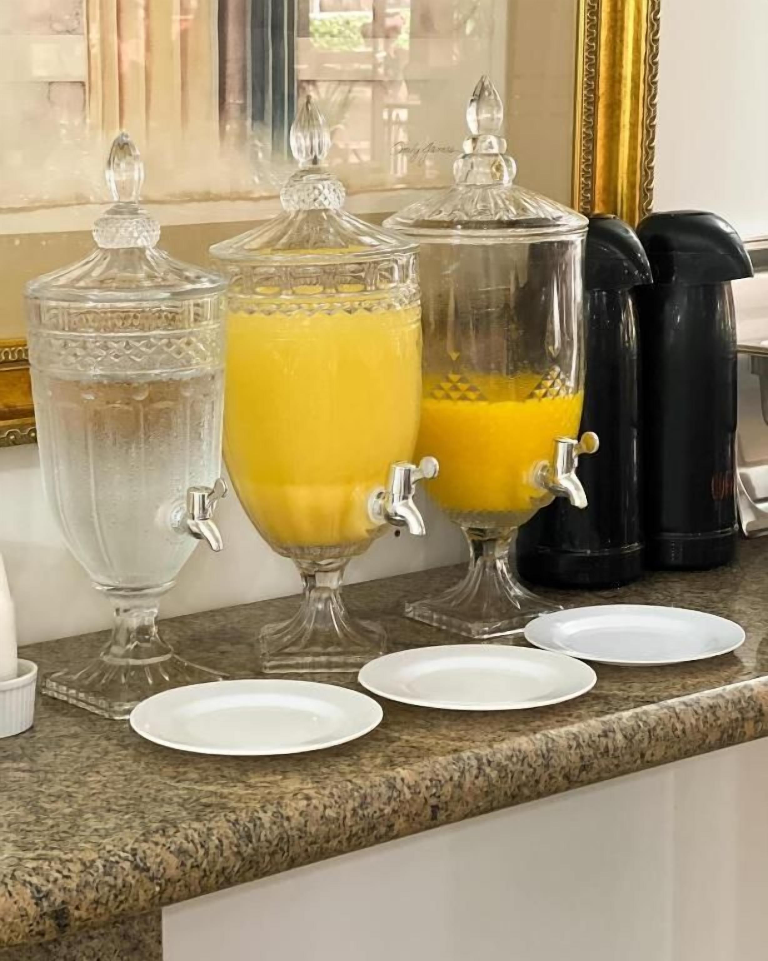A kitchen counter with two glass dispensers, one with a clear liquid and one with a yellow liquid, and a black coffee maker.