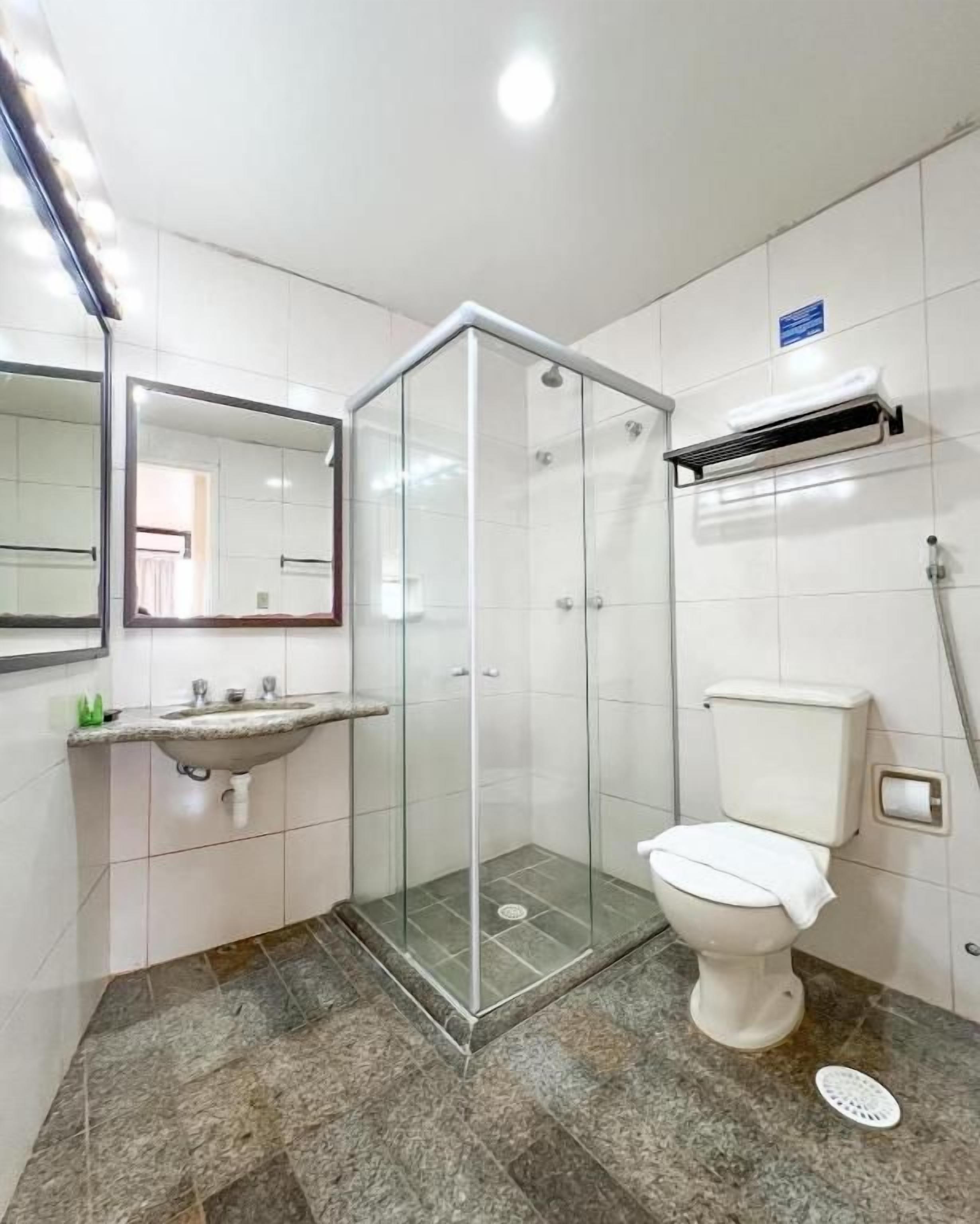 A bathroom with a glass-enclosed shower, a sink with a mirror, and a toilet.