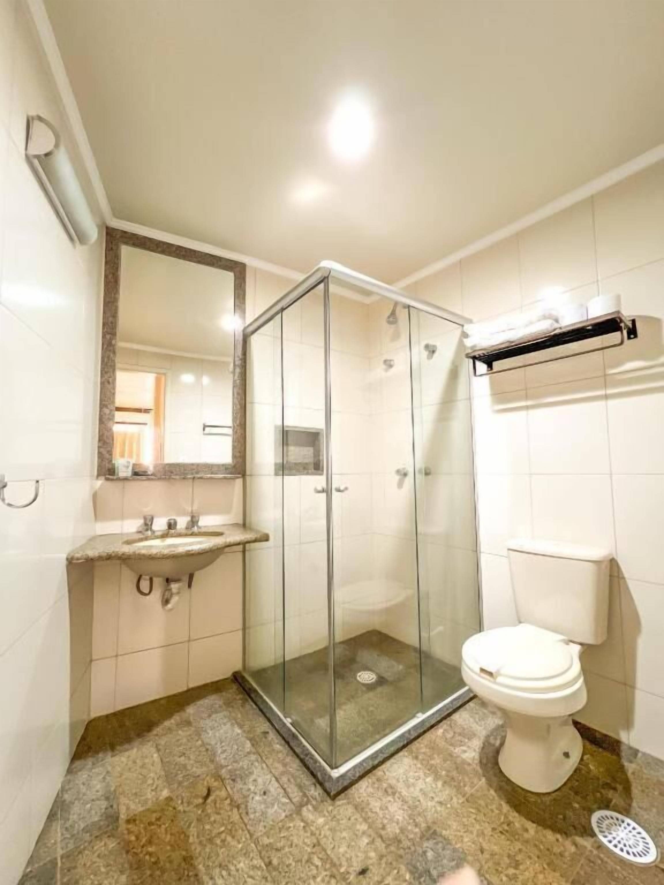 Une salle de bain avec une douche à parois de verre, un lavabo, des toilettes et un porte-serviettes.