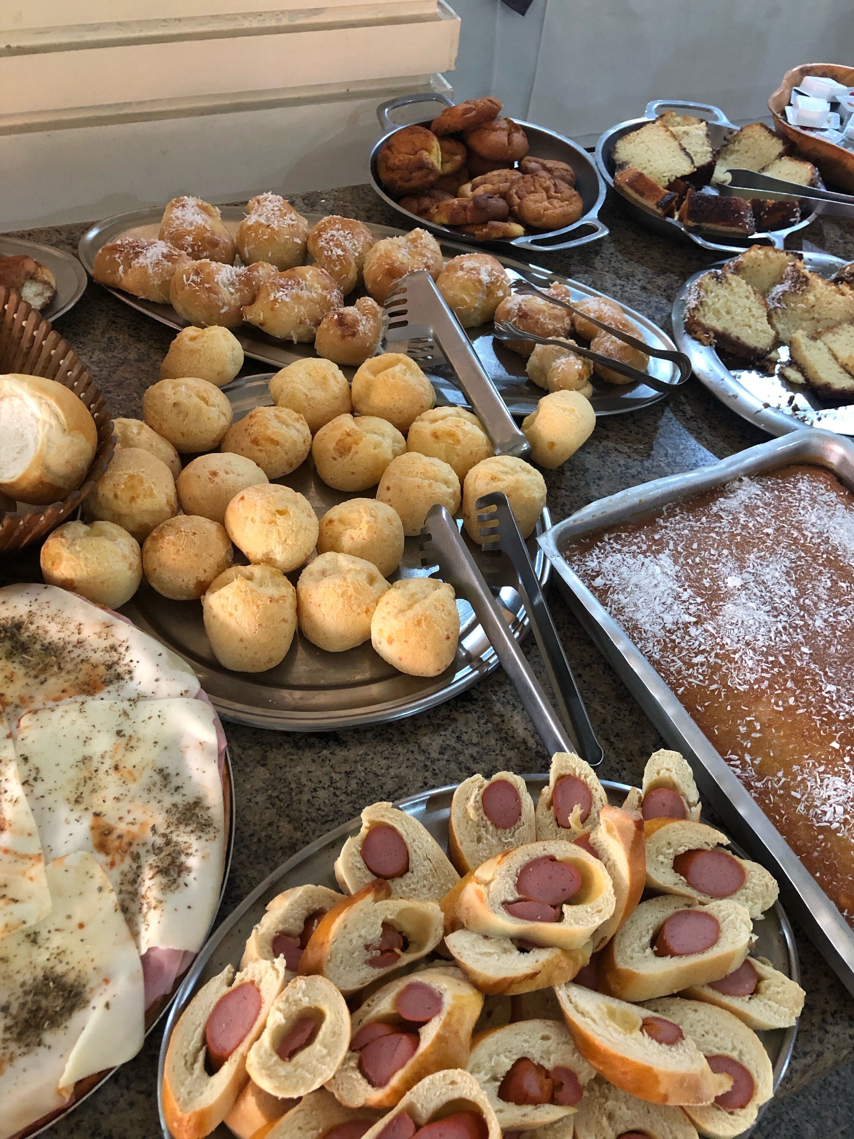 Een buffet met diverse gebakken producten, waaronder broodjes, gebak en worstdijen.