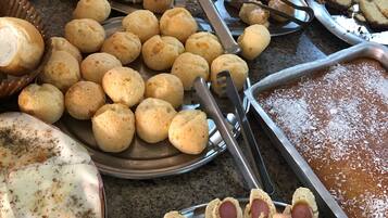 Een buffet met diverse gebakken producten, waaronder broodjes, gebak en worstdijen.