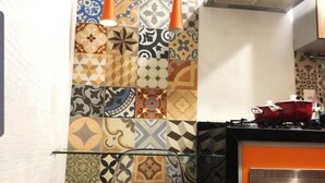 A kitchen with a tiled backsplash featuring various geometric patterns, a stainless steel range hood, and a red pot on the stove. - Peace house near the beach (Boqueirão)