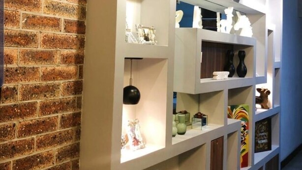 A modern interior with exposed brick walls, white shelving units, and various decorative items. - Peace house near the beach (Boqueirão)