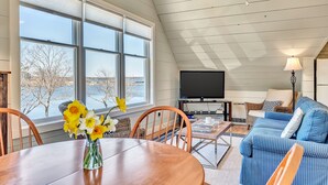 A spacious living room with a large window, a ceiling fan, a TV, and a blue-striped sofa.