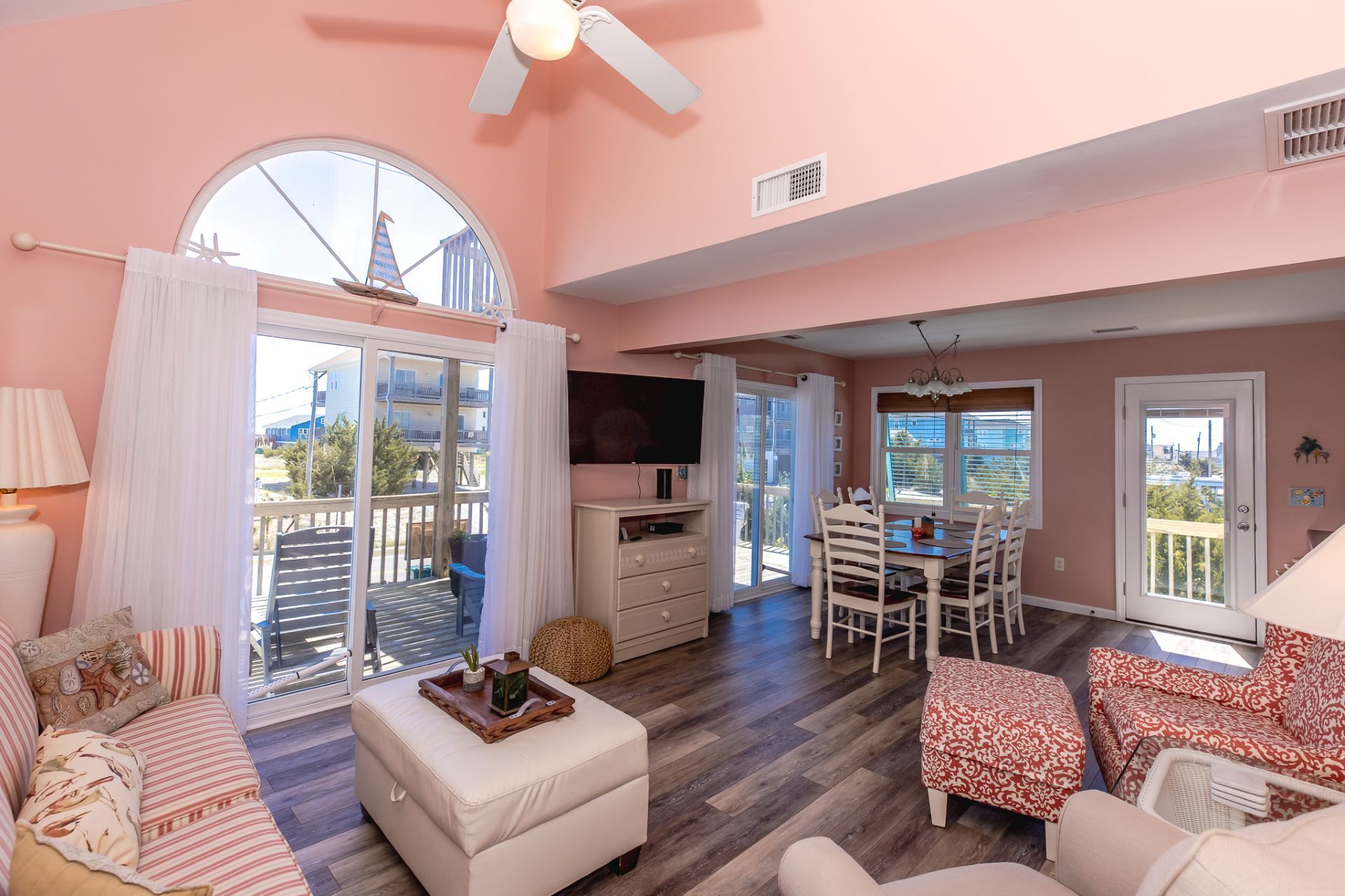 A spacious living area with a balcony, a dining set, and a television.