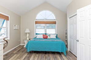 A bedroom with a bed, a nightstand, a lamp, a window with blinds, and a door. - Sea K's - 3 bedroom, 2 bath home in Topsail Beach! Dog Friendly! (Topsail Beach)