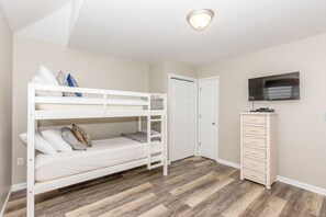 A room with a bunk bed, a wardrobe, and a television.