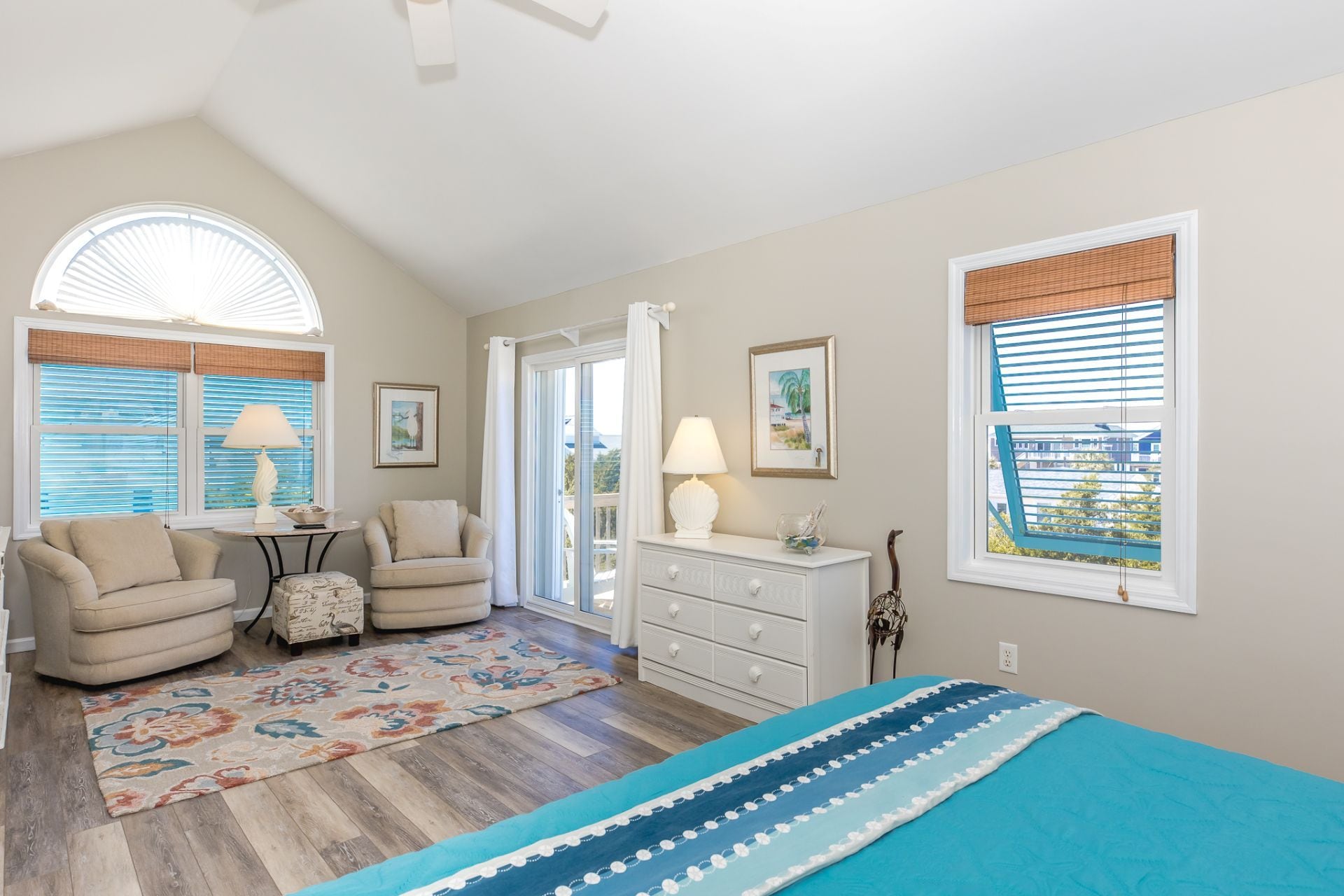 A bedroom with a bed, a chair, a dresser, and a window with blinds.