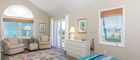 A bedroom with a bed, a chair, a dresser, and a window with blinds.