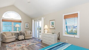 A bedroom with a large window, a dresser, a chair, a small table, and a bed. - Sea K's - 3 bedroom, 2 bath home in Topsail Beach!  Dog Friendly! (Topsail Beach)