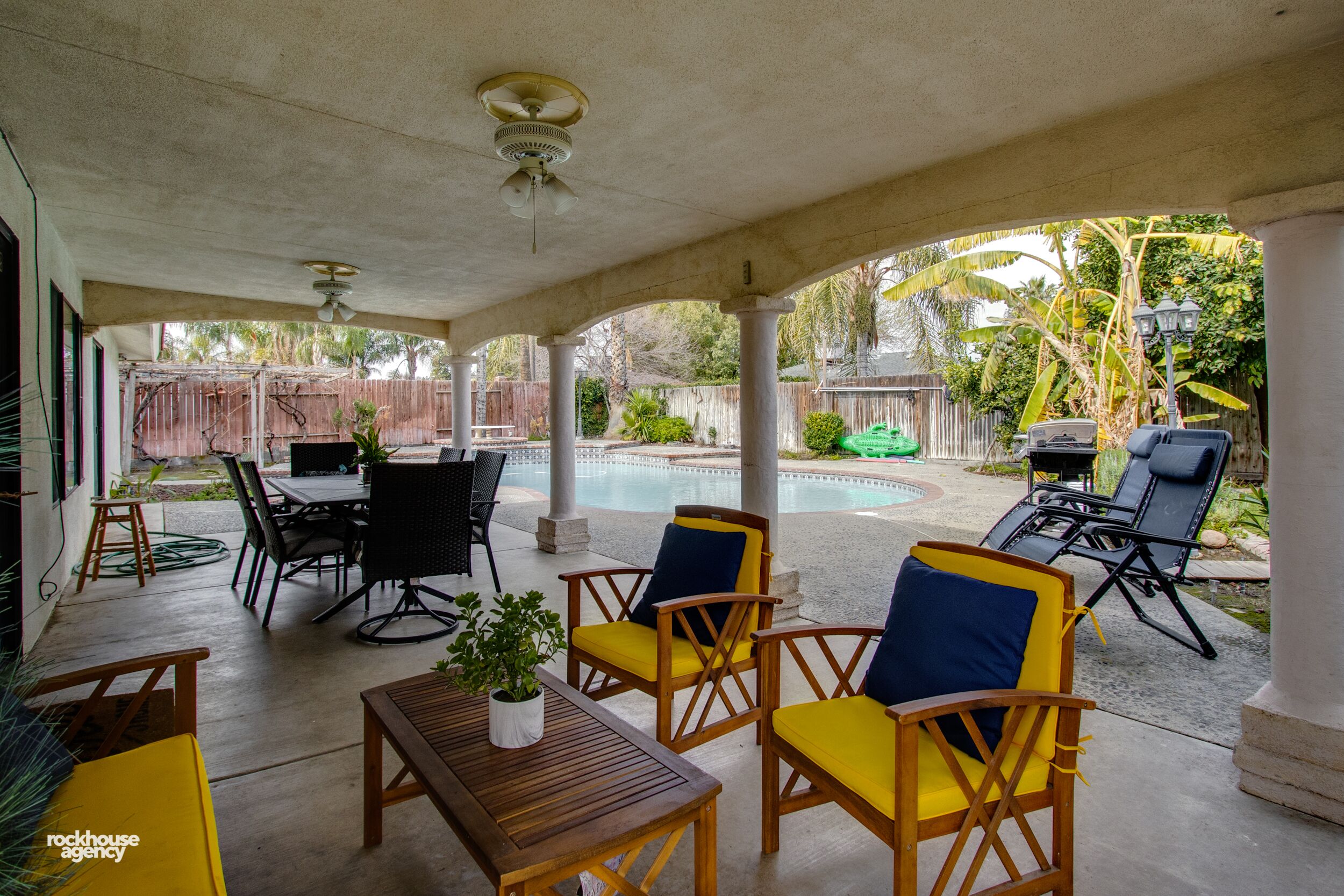 Un patio couvert aménagé avec du mobilier d’extérieur, une piscine et un barbecue.