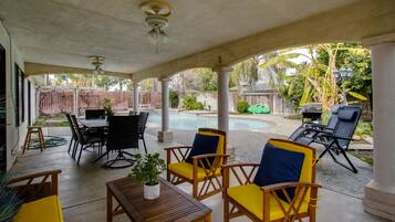 Un patio couvert aménagé avec du mobilier d’extérieur, une piscine et un barbecue.