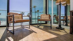 Een balkon met twee leren stoelen, een vloerlamp en uitzicht op de oceaan.