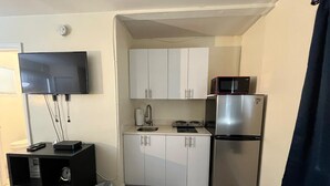 Una kitchenette compacta equipada con microondas, refrigerador y un lavamanos pequeño.