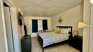 Un dormitorio con cama, mesita de noche, lámpara y un adorno en la pared.