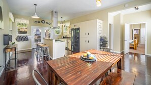 A spacious kitchen with a wooden dining table, a refrigerator, and a built-in oven. - The Fun House! Hot tub, Espresso Bar, Views, Foosball, Fire Pit, More! (Durango)