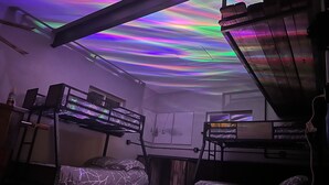 A dormitory room with bunk beds, a desk, and a ceiling projector displaying a colorful light show. - The Fun House! Hot tub, Espresso Bar, Views, Foosball, Fire Pit, More! (Durango)