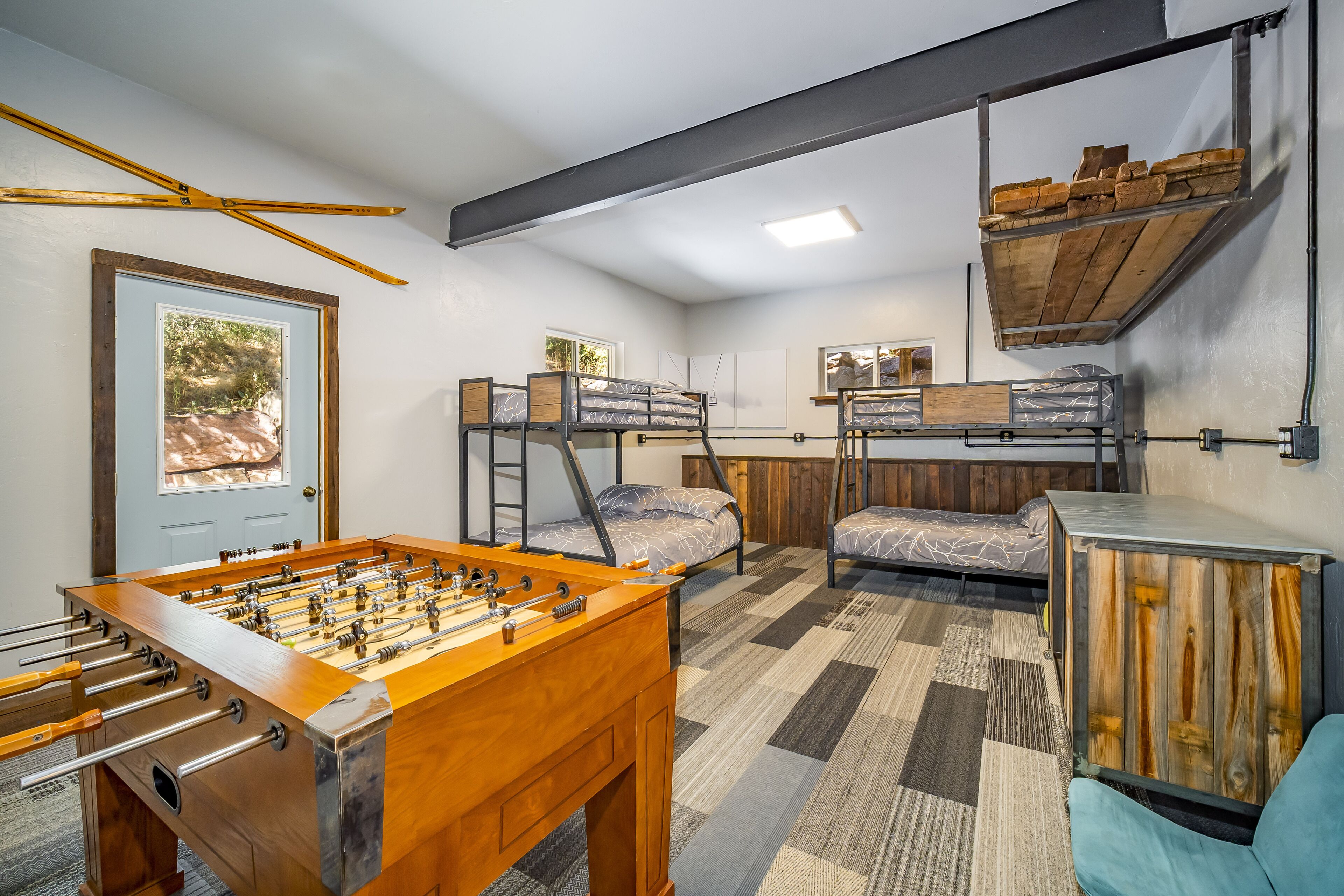 A room with bunk beds, a foosball table, and a window with a view.