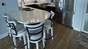 A modern kitchen with a central island, stainless steel appliances, and a clock on the wall.