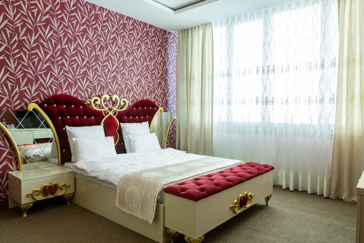 A bedroom with a large bed, a nightstand, and a dresser.