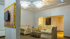 Un salón lujoso con muebles ornamentales, un televisor de pantalla plana en la pared y una araña.