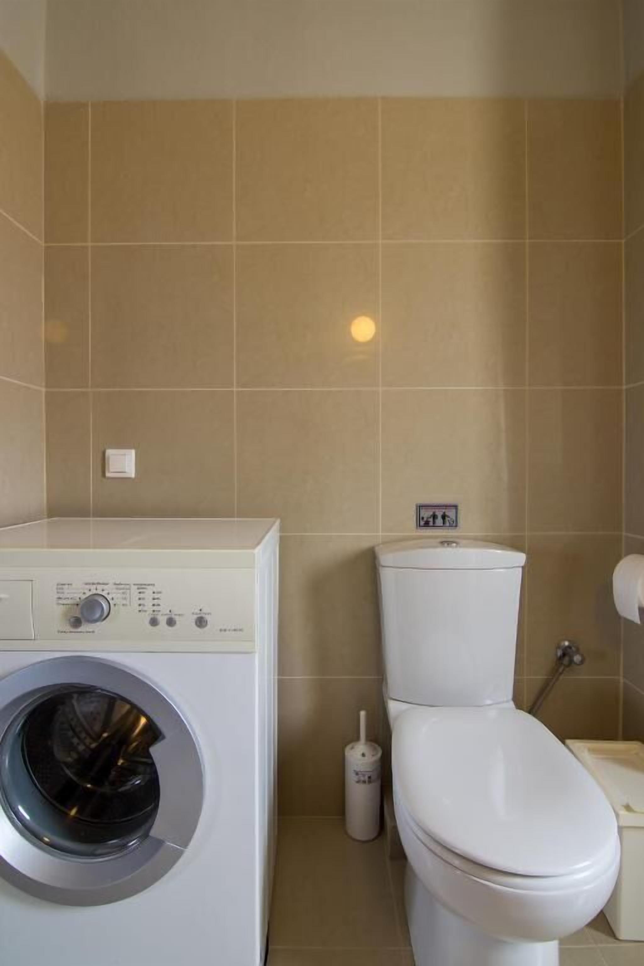 Un baño con lavadora, inodoro y secador de manos.