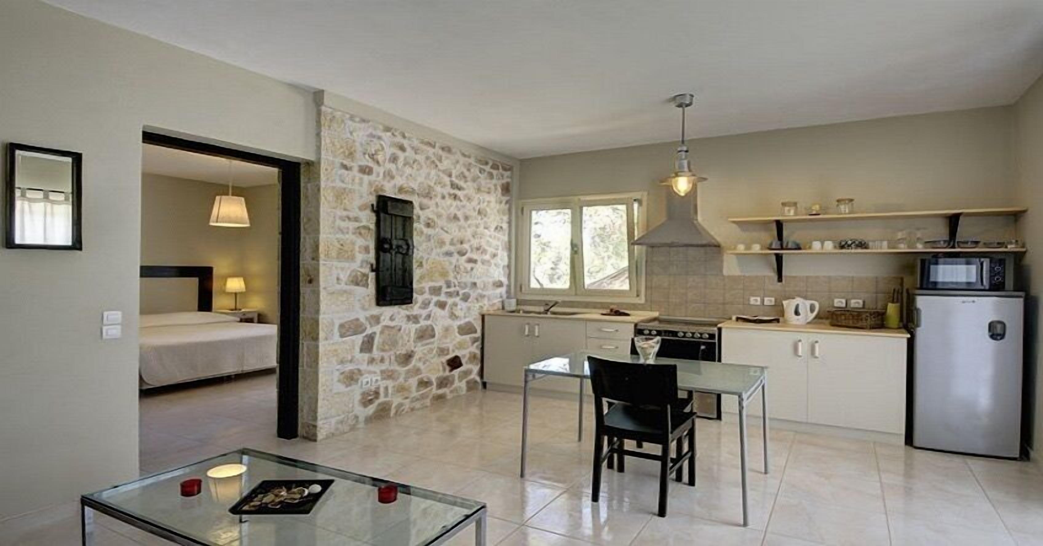 A compact hotel room with a kitchenette, a dining area, and a bed.