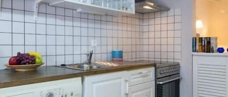 Kompakti keittiö, jossa on mikroaaltouuni, uuni, pesukone ja pesuallas.