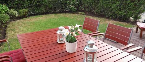 A red wooden table with two chairs, a potted plant, and two lanterns.
