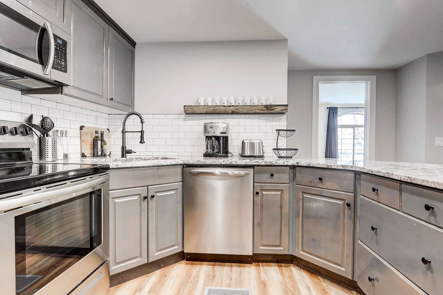 A modern kitchen with stainless steel appliances, a dishwasher, and a wooden countertop.