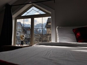 A bedroom with a large window, a bed, and a lamp.