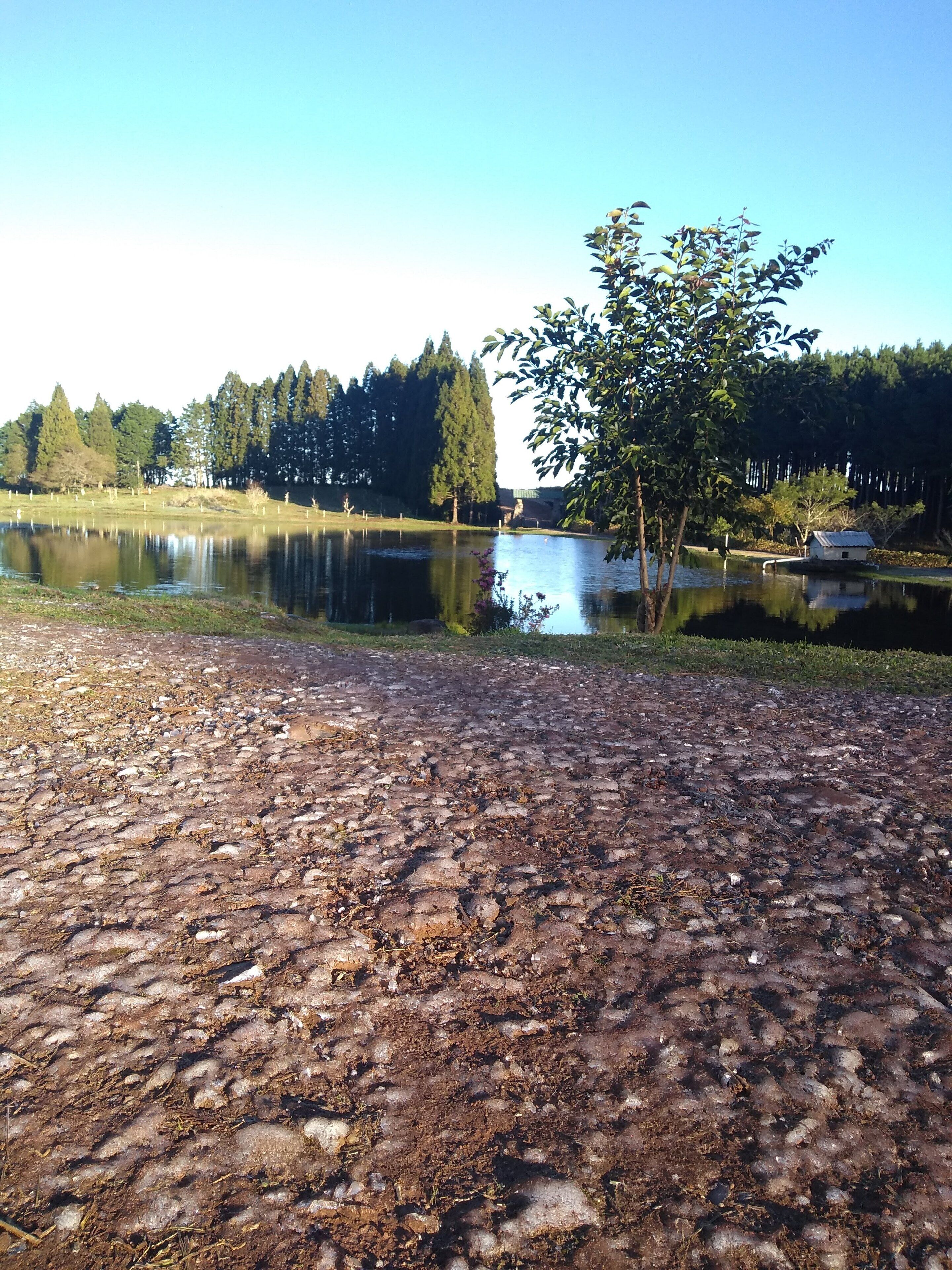 A lake with a rocky shoreline and a small building near the water's edge.