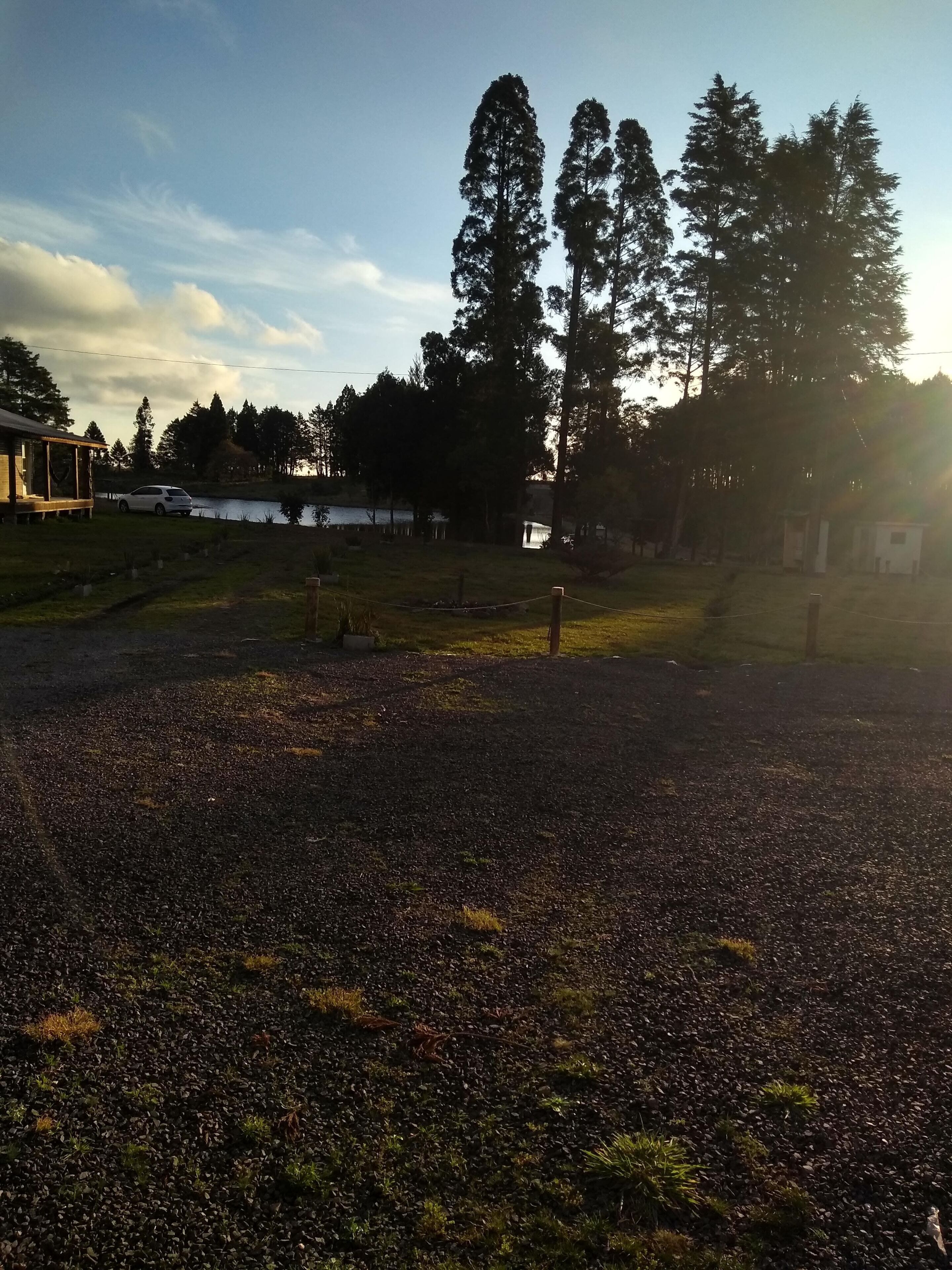 Ein Kiesparkplatz mit einem kleinen Gebäude und einem weißen Auto in der Nähe.